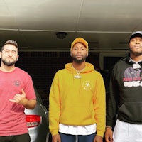 three men standing in front of a car