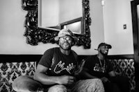 two men sitting on a couch in front of a mirror