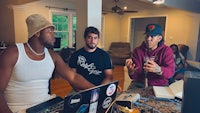 three men sitting around a table with laptops