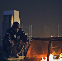 a man sitting on top of a fire pit at night