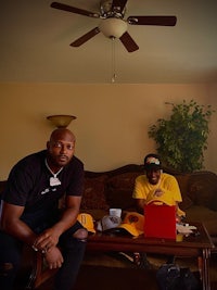 two men sitting on a couch in a living room