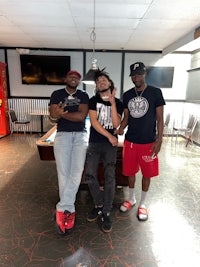 three men standing in front of a pool table