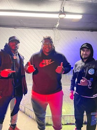 three men posing for a picture in a garage