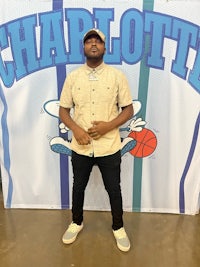 a man standing in front of a charlotte basketball banner